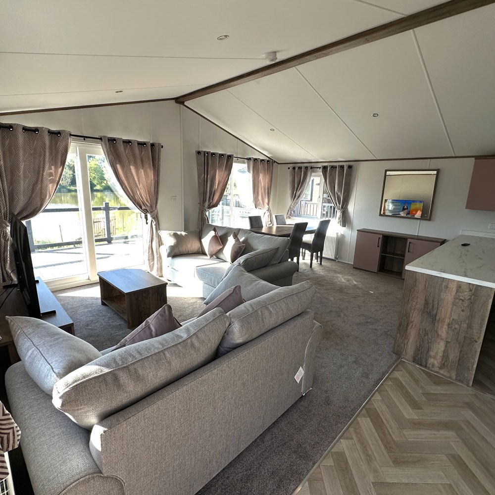 Open-plan living and dining area with patio doors onto lake-view decking