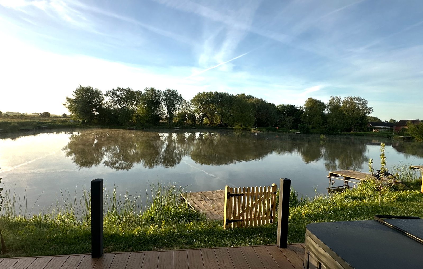Morning mist rising off the fishing lake, seen from a lodge decking