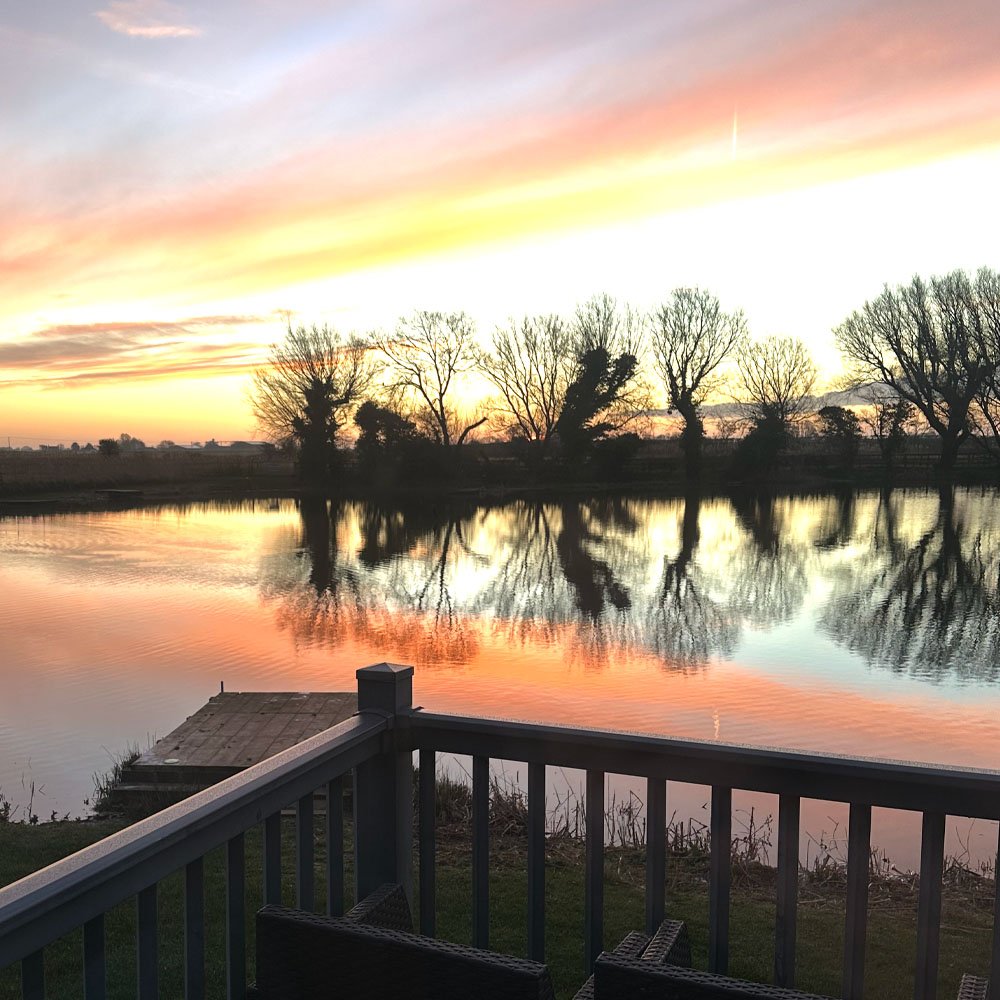Sunset colour spread across the lake, seen from a lodge decking