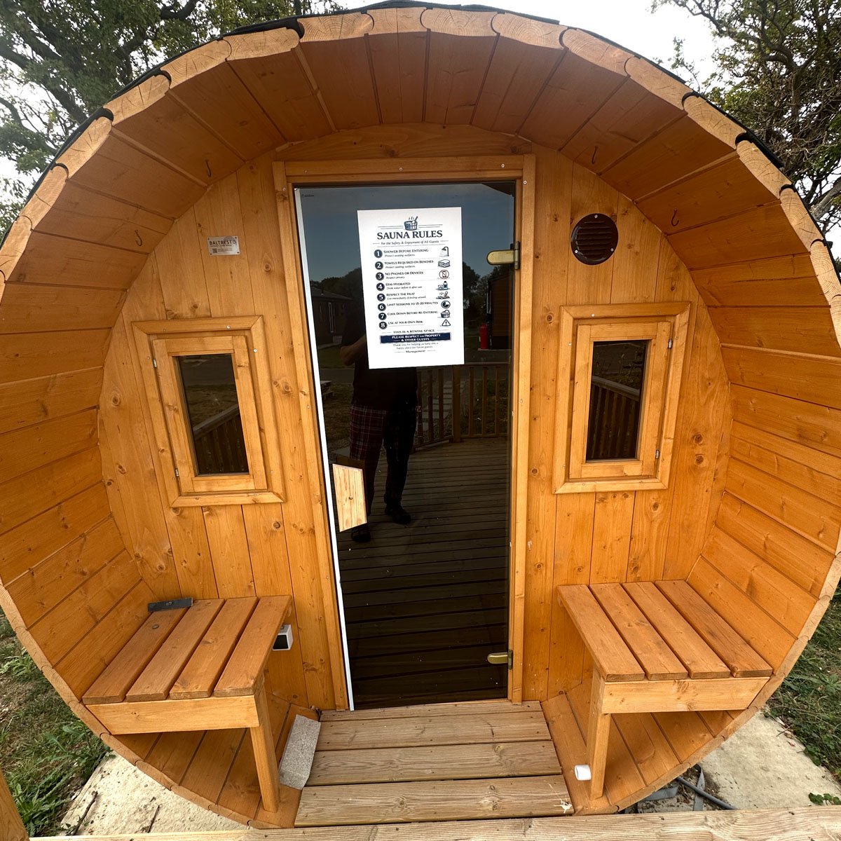 The rounded timber end of the sauna, with a bench seat either side of the open door